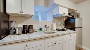 A modern kitchen with white cabinets, a marble countertop, a built-in oven, and a stainless steel refrigerator. - Walk to Light Rail: Quiet Judkins Park Home Base! (Seattle)