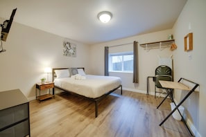 A bedroom with a bed, bedside table, lamp, and a small desk. - Walk to Light Rail: Quiet Judkins Park Home Base! (Seattle)