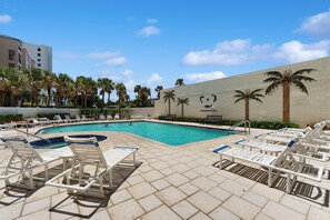 A pool area with lounge chairs and palm trees. - Ocean-view Balcony, Pool! New Smyrna Beach Escape (New Smyrna Beach)