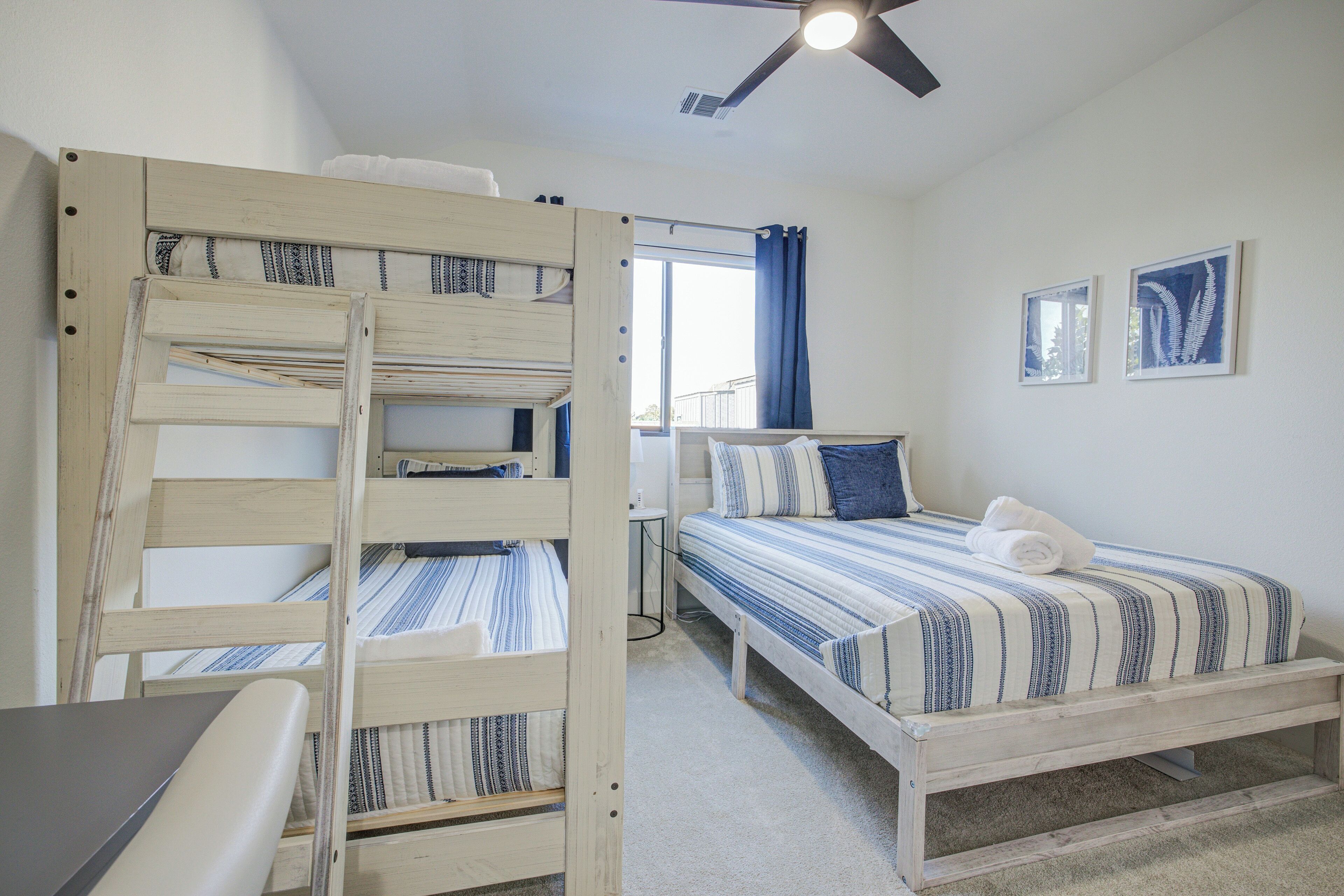 A room with bunk beds, a desk, and a ceiling fan.