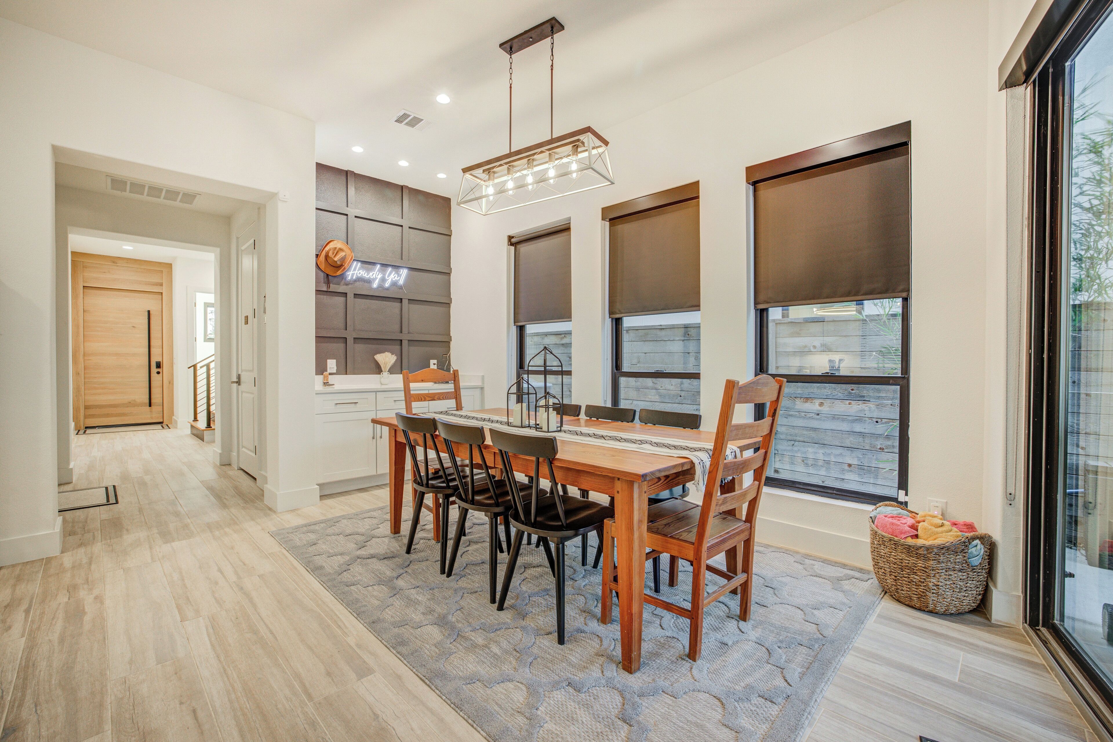 A modern dining area with a wooden table, chairs, and a hanging light fixture.