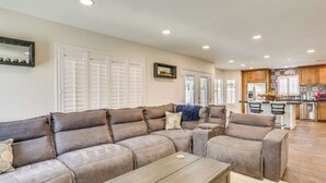A spacious living room with a large sectional sofa, a coffee table, and a kitchen area in the background. - 4BR Home w/ Private Pool, Patio & Grill (Glendale)
