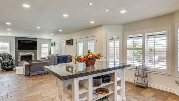 A spacious living area with a fireplace, a comfortable sofa, and a kitchen island with a vase of flowers. - 4BR Home w/ Private Pool, Patio & Grill (Glendale)