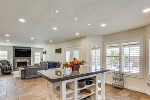 A spacious living area with a fireplace, a comfortable sofa, and a kitchen island with a vase of flowers. - 4BR Home w/ Private Pool, Patio & Grill (Glendale)