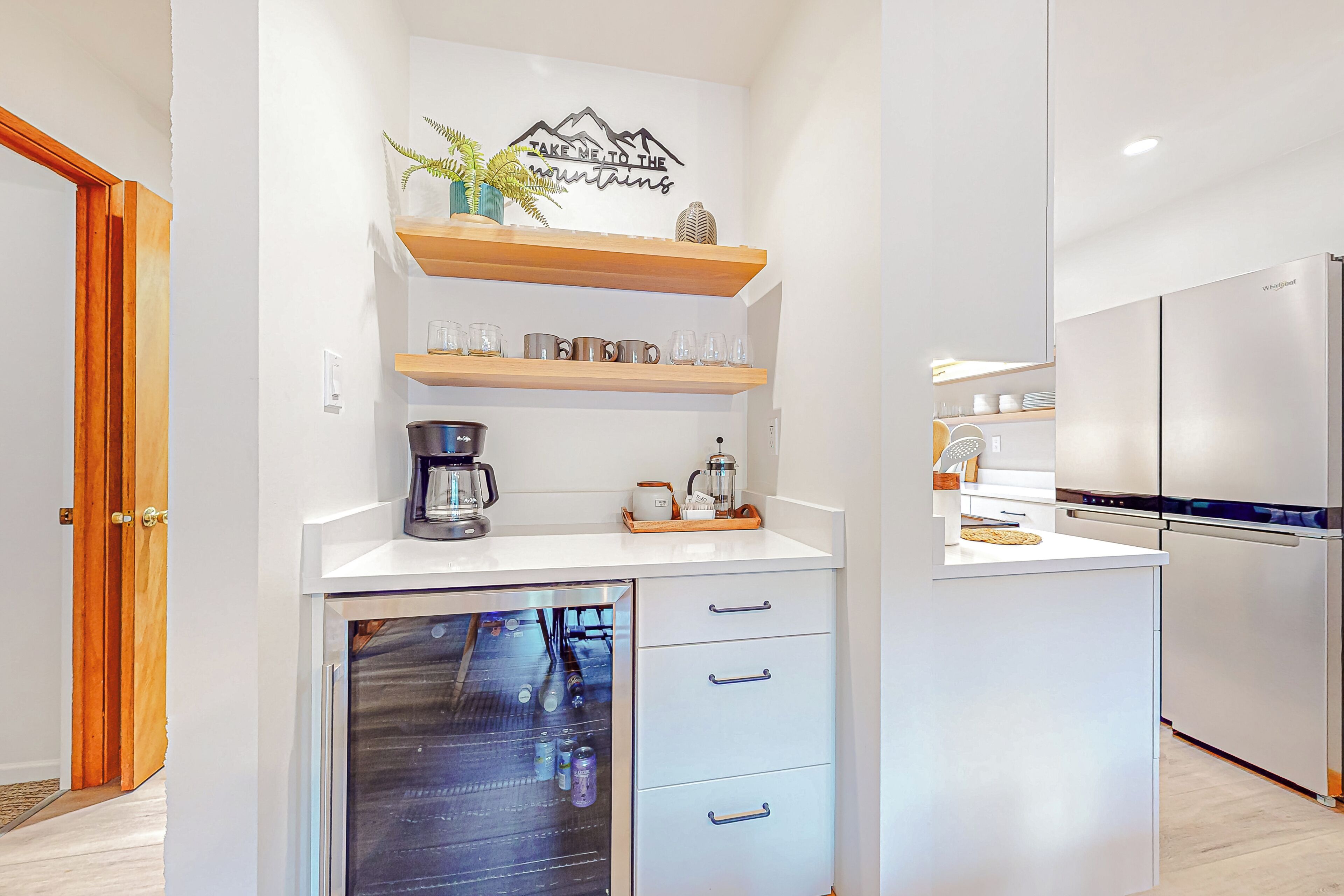 A compact kitchen with white cabinetry, a built-in dishwasher, and a stainless steel refrigerator.