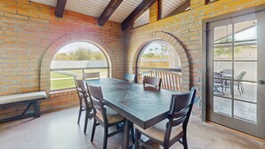 A dining area with a brick wall, wooden beams, and a large window. - Peaceful, Spacious, Luxury Backyard, Putting Green (Scottsdale)