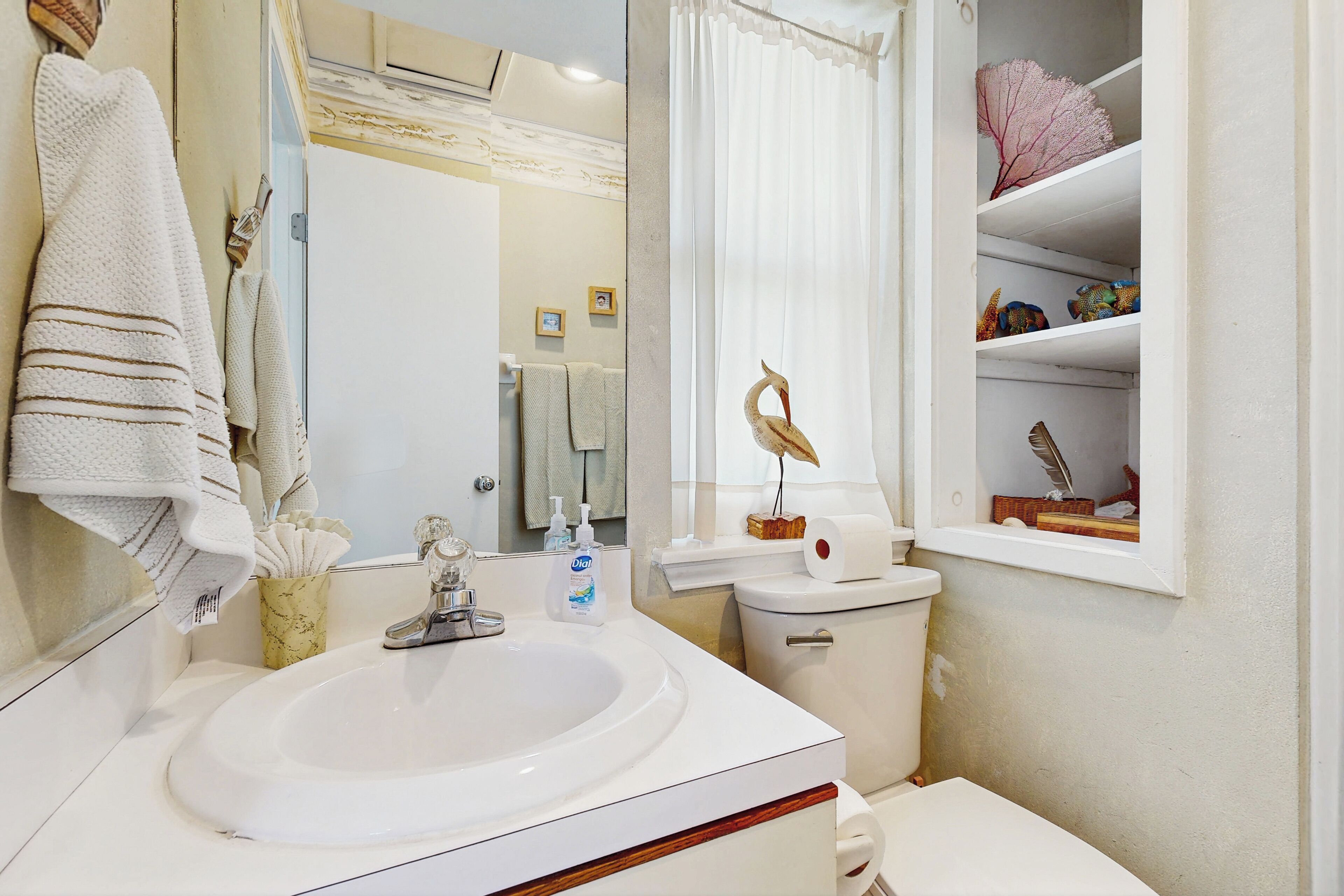 Een badkamer met een witte wastafel, toilet en een plank met decoratieve objecten.