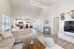A spacious living room with a large sofa, a wooden coffee table, and a television. - 2 BR Condo w/ Golf Course Views & Pool (Myrtle Beach)