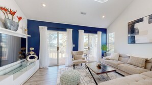 Una sala moderna con una pared azul de acento, una mesa de centro de vidrio y un sofá color beige.
