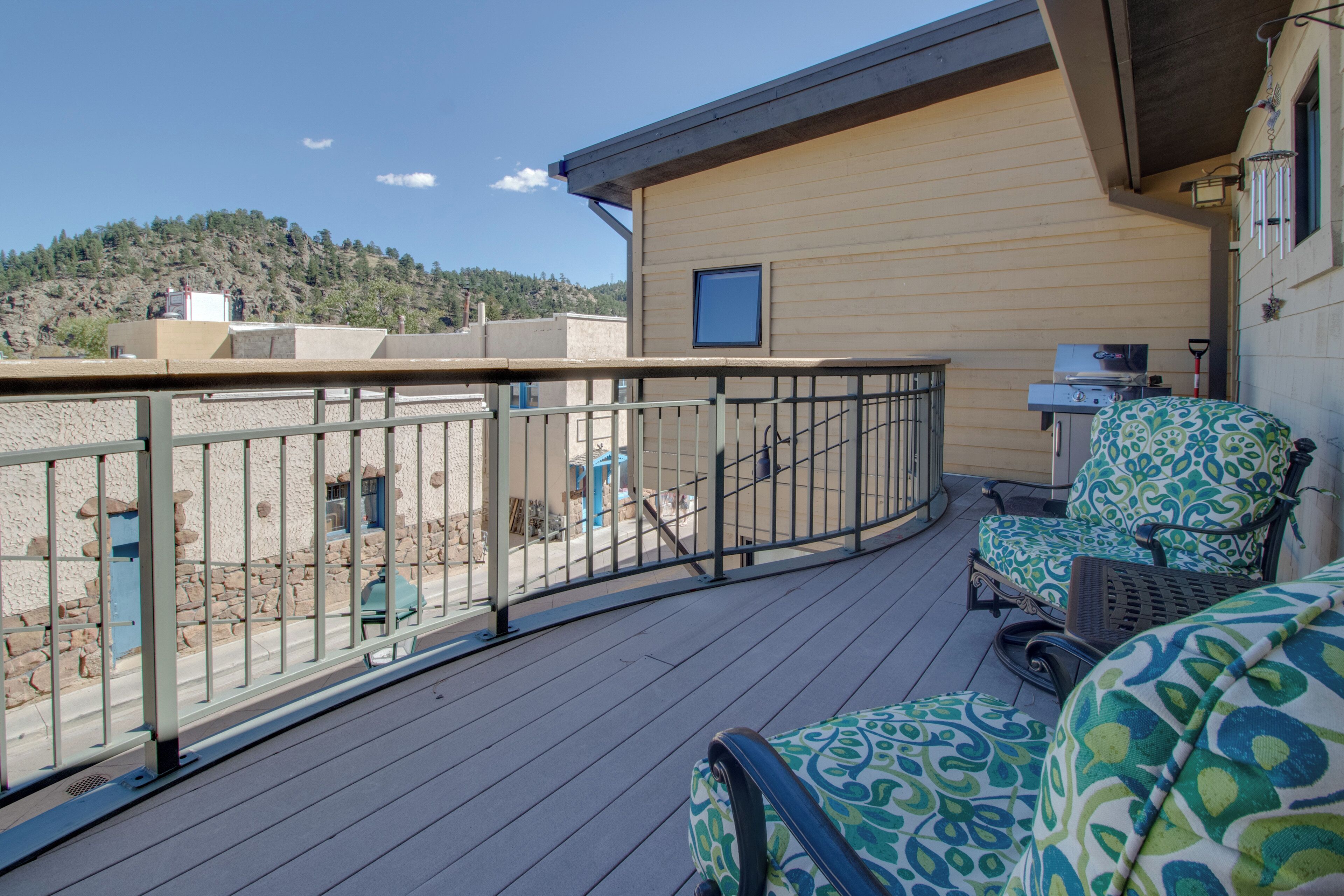 A balcony with a metal railing, a chair, and a small table.