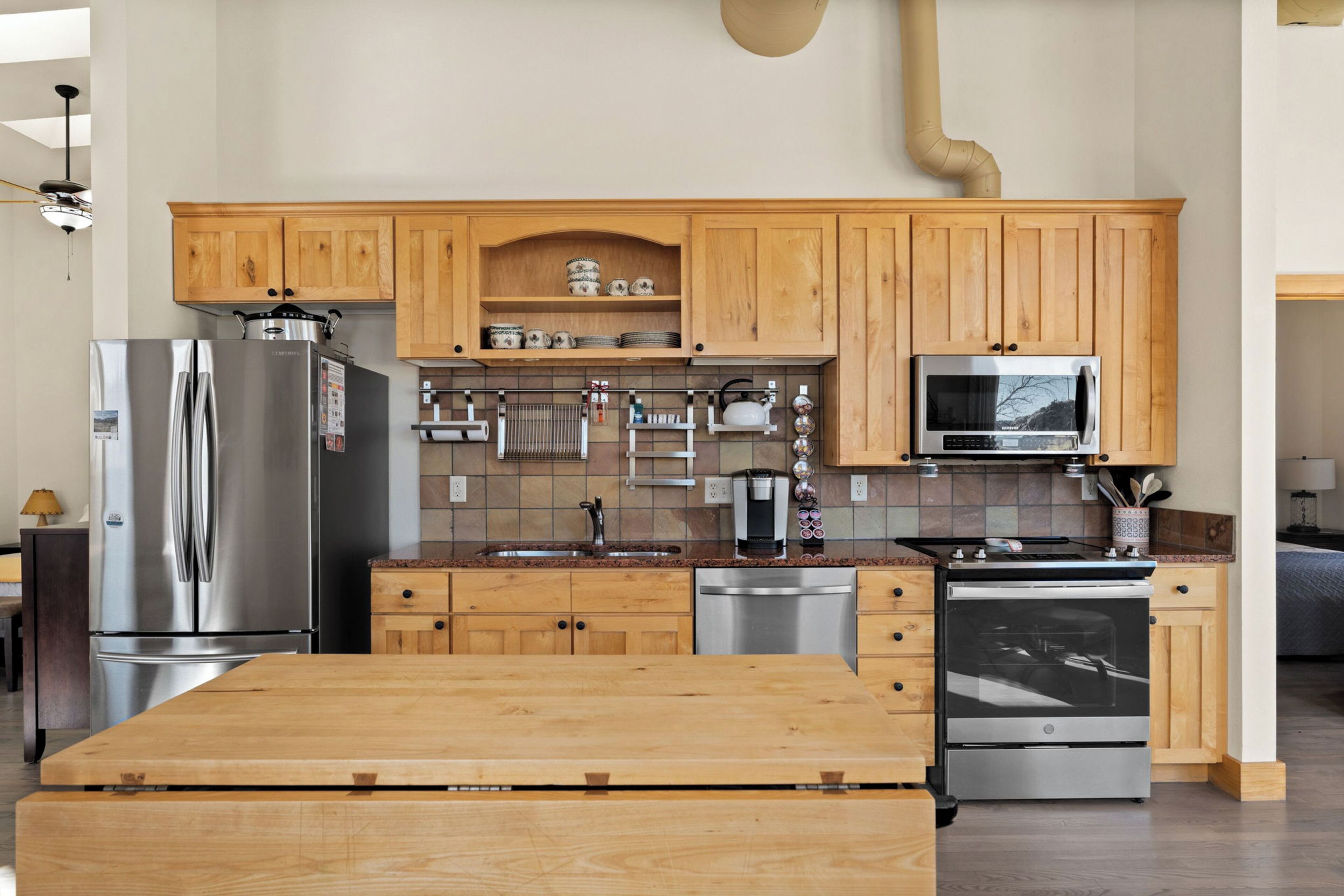 A modern kitchen with wooden cabinets, stainless steel appliances, and a central island.