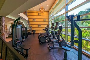 Ein Fitnessstudio mit Cardiogeräten, Gewichten und einer Treppe.
