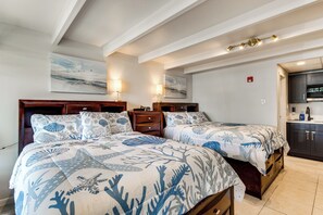 Ein Schlafzimmer mit zwei Betten, einem hölzernen Kopfteil, einem Nachttisch, einer Wandlampe und einem Gemälde.