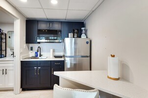 A compact kitchen with dark cabinets, a stainless steel refrigerator, a coffee maker, and a paper towel holder.