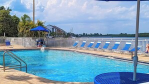 A swimming pool with blue chairs and a covered area with an umbrella. - Dolphin & Manatee Cove Condo: Beach Access + More! (Ruskin)
