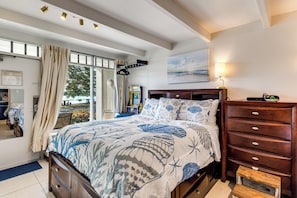 Une chambre à coucher avec un lit, une commode, une table de chevet, une lampe et un tableau accroché au mur.