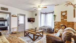 A living room with a wooden coffee table, leather sofa, and a TV mounted on the wall. - Wine, Dine & Unwind: Hermann Home w/ Spacious Yard (Hermann)