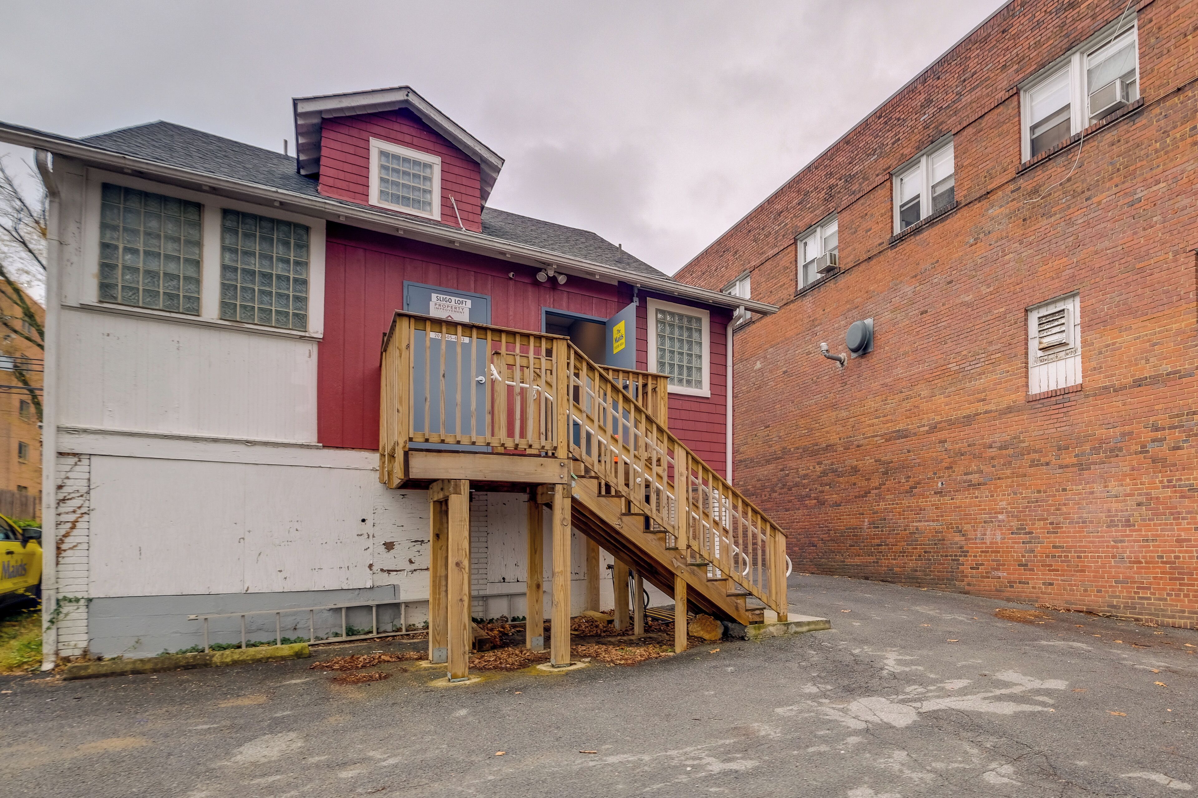 A red building with a wooden staircase leading to a deck.