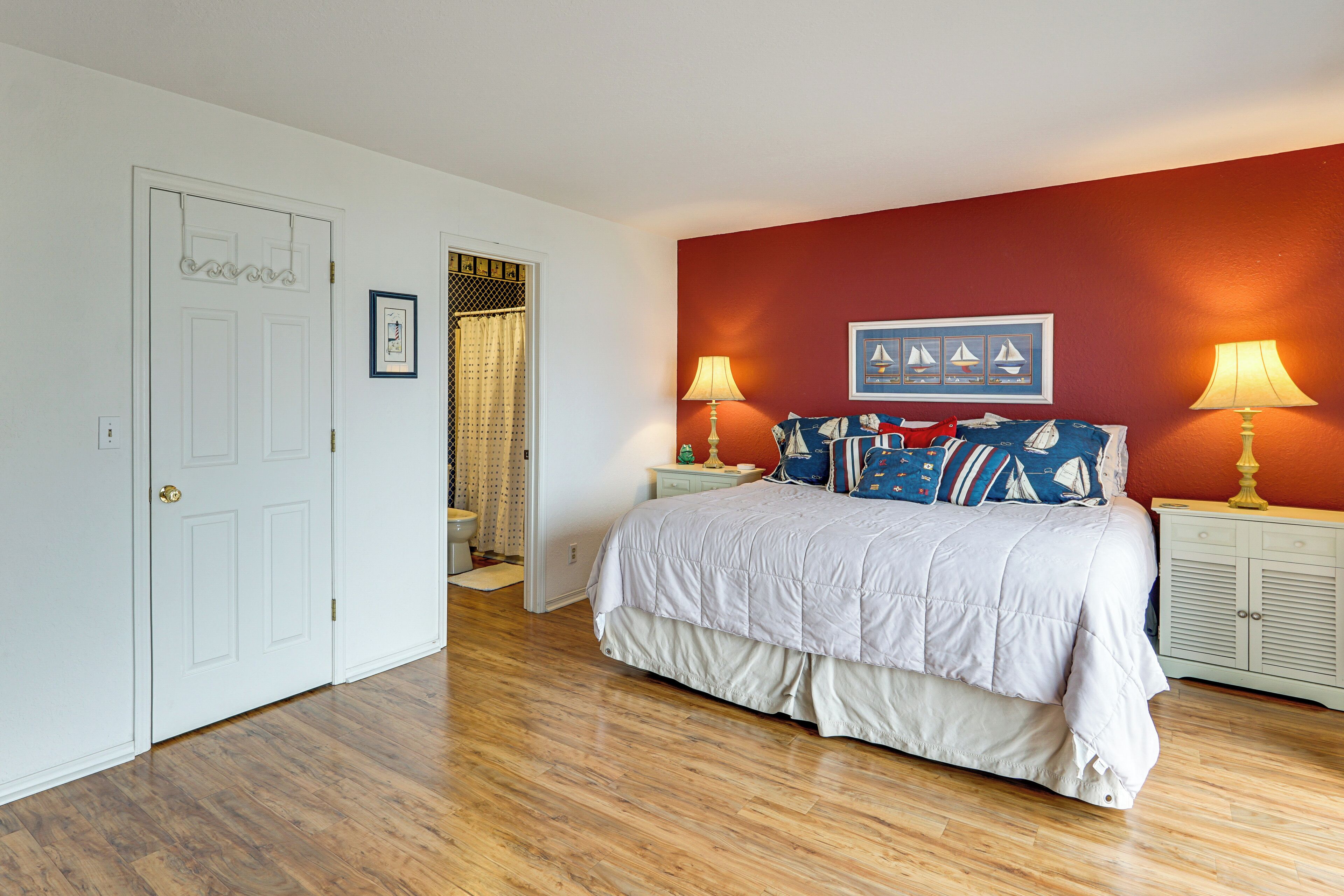 A bedroom with a bed, two bedside tables, a door, and a window with curtains.