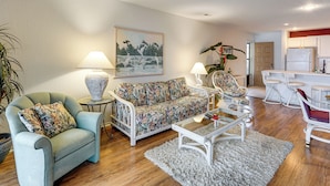 Ein Wohnzimmer mit Sofa, Sesseln, Couchtisch und einem Gemälde an der Wand.