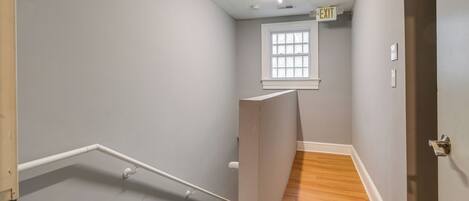 A staircase with a wooden finish and white handrails, leading to a landing with a window.