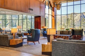 Un hall d’entrée spacieux, doté de grandes fenêtres offrant une vue sur les montagnes, de sièges confortables et d’un lustre moderne.