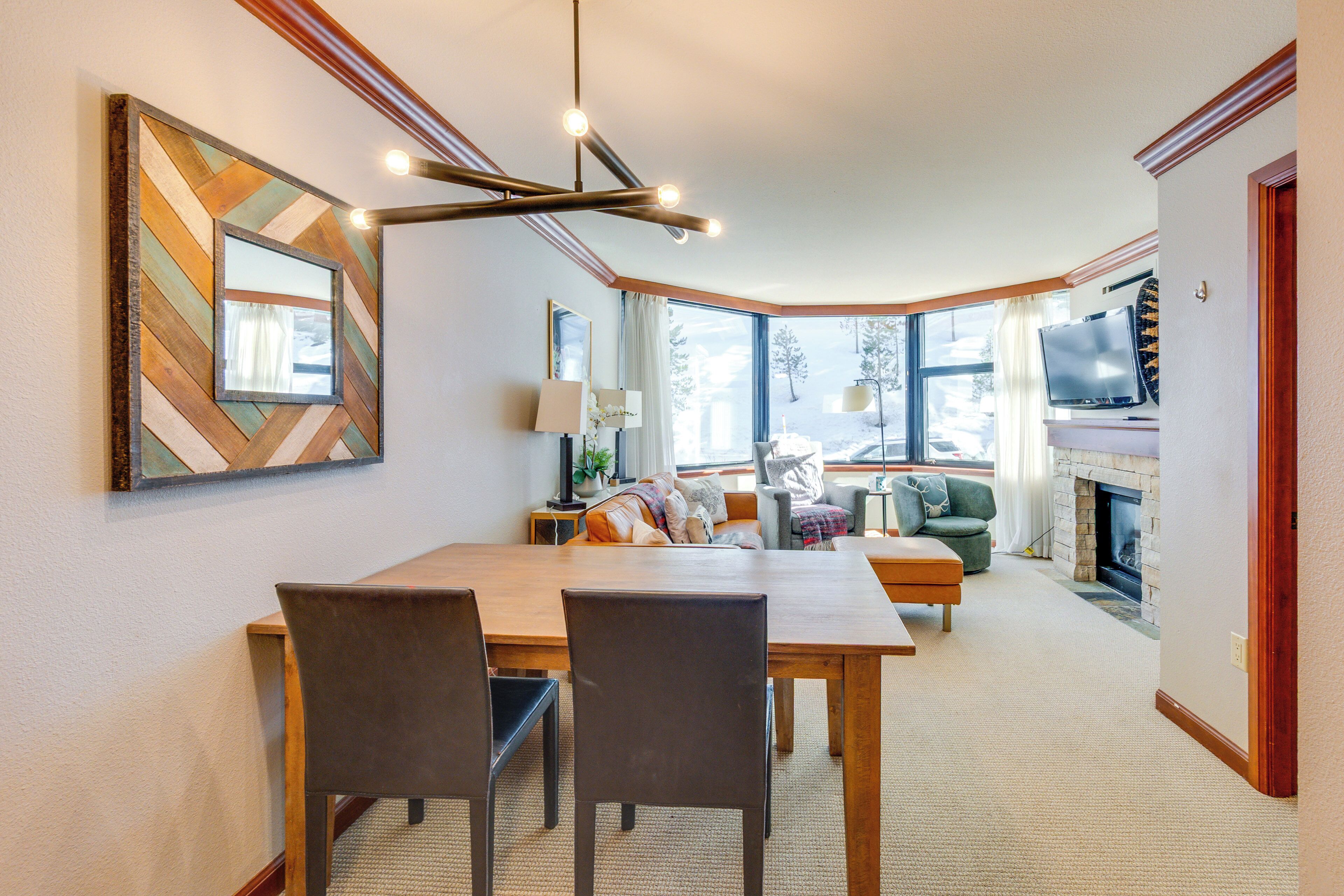 Un amplio salón con una mesa de comedor de madera, dos sillas, un sofá y un televisor.