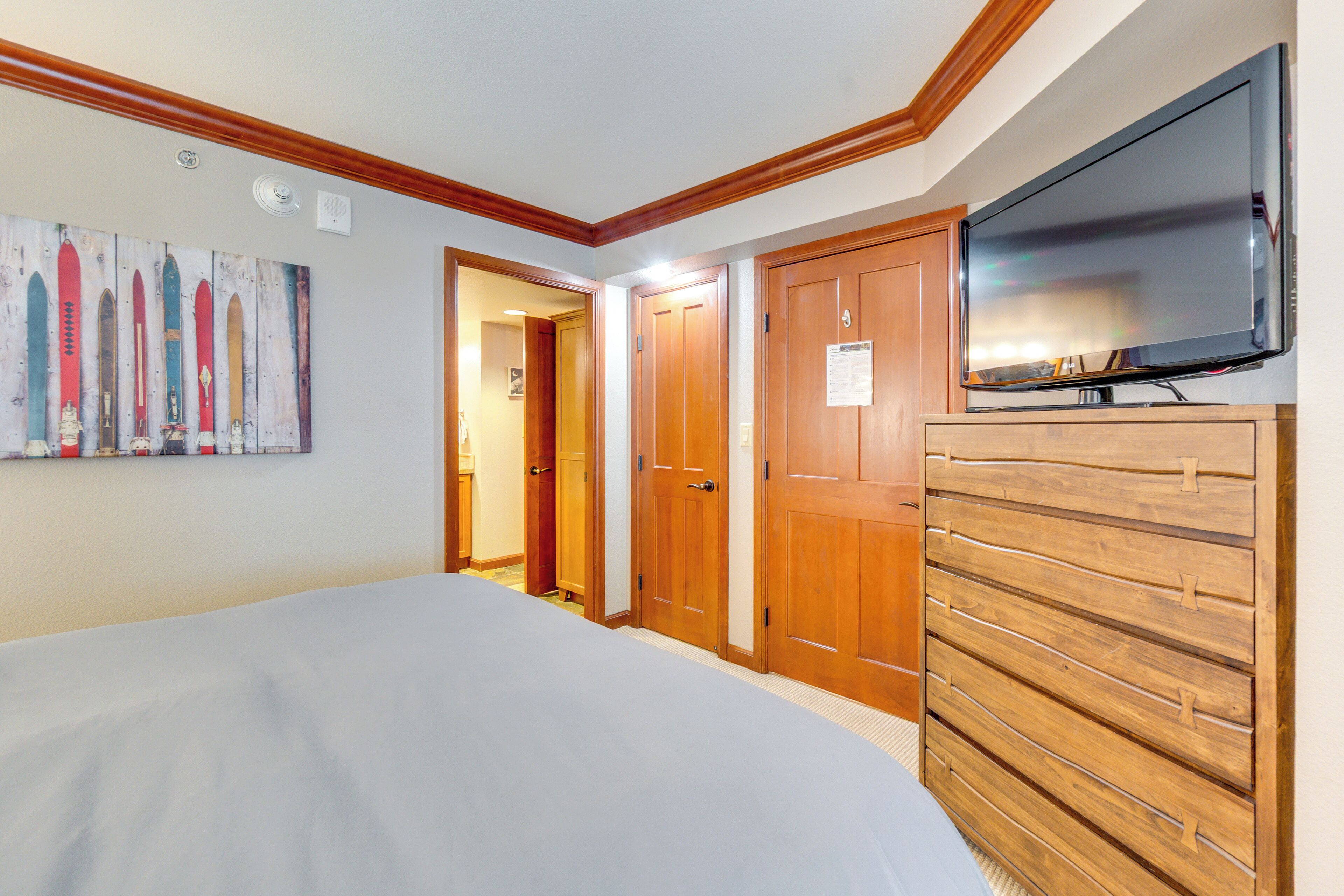 Une chambre à coucher avec un lit, une armoire en bois et un téléviseur.