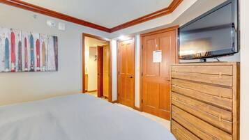 Une chambre à coucher avec un lit, une armoire en bois et un téléviseur.