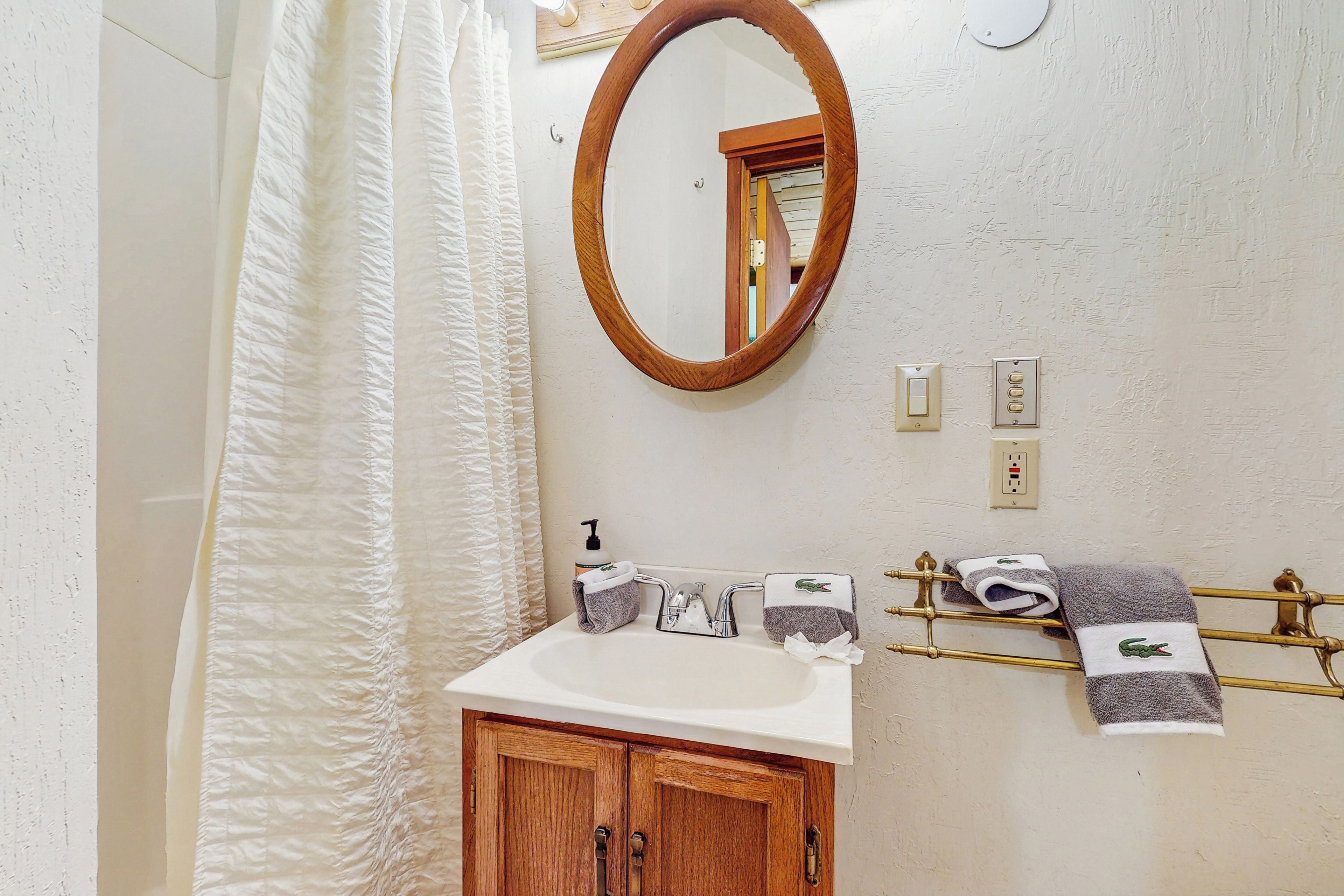 Un bagno con un armadietto in legno, un lavandino bianco, uno specchio e un porta asciugamani con asciugamani.
