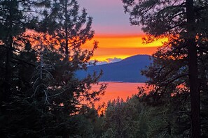 A sunset view through a forest with a mountain in the background. - 2BR Dog-friendly Cabin w/ Lake Views (Kings Beach)