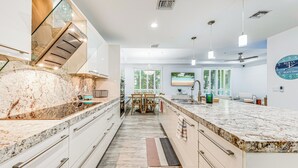 A modern kitchen with white cabinetry, granite countertops, and a central island. - Walk to Hollywood Beach: Luxury Family Getaway! (Hollywood)