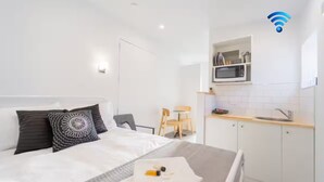Ett modernt hotellrum med en säng, ett nattduksbord och ett litet pentry.