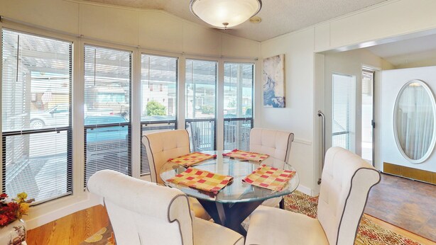 A dining area with a glass table, four chairs, and a chandelier. - Manufactured w/ Pools, Hot Tubs, Pickleball, AC (Surprise)