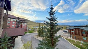 A residential area with a multi-story building, a single-story building, and a prominent evergreen tree. - Granby Ranch Condo w/ Mtn-view: Trails & Hot-tub! (Granby)