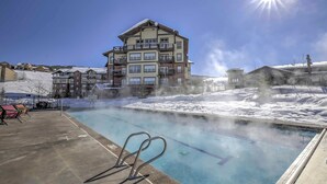 A pool area with a clear sky and a multi-story building in the background. - Granby Ranch Condo w/ Mtn-view: Trails & Hot-tub! (Granby)