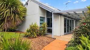 A modern house with a covered patio, a garden with various plants, and a clear sky. - Aldebaran Road Beach House - perfect family coastal getaway, your search ends here (Ocean Grove)