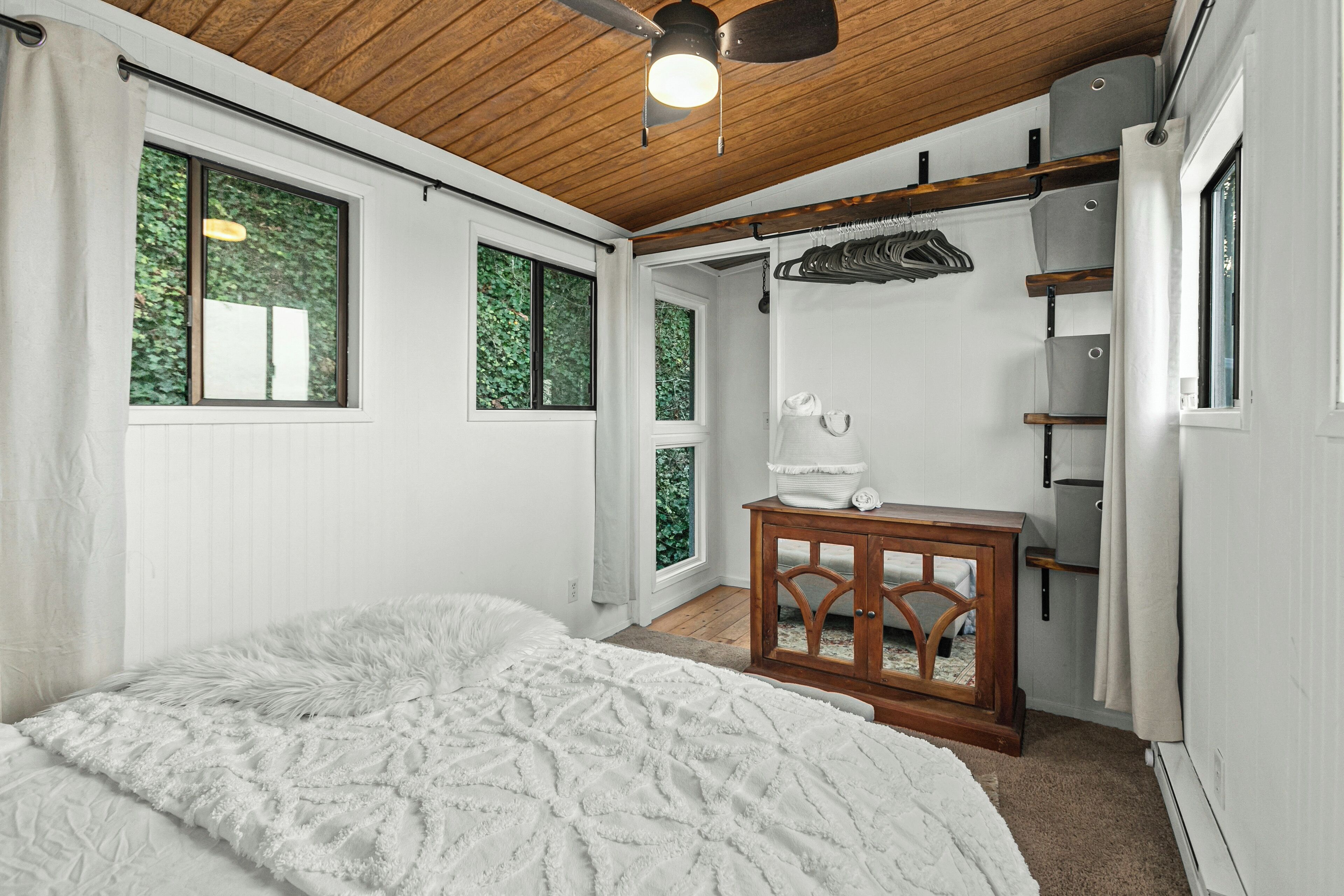 Un dormitorio con una cama grande, techo de madera y ventana con vistas a zonas verdes.