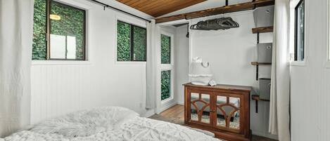 Un dormitorio con una cama grande, techo de madera y ventana con vistas a zonas verdes.