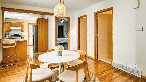 A modern kitchen with wooden cabinets, a dining area with a round table and chairs, and a ceiling light fixture. - Pet-friendly Home 2 Mi to Downtown Des Moines! (Des Moines)