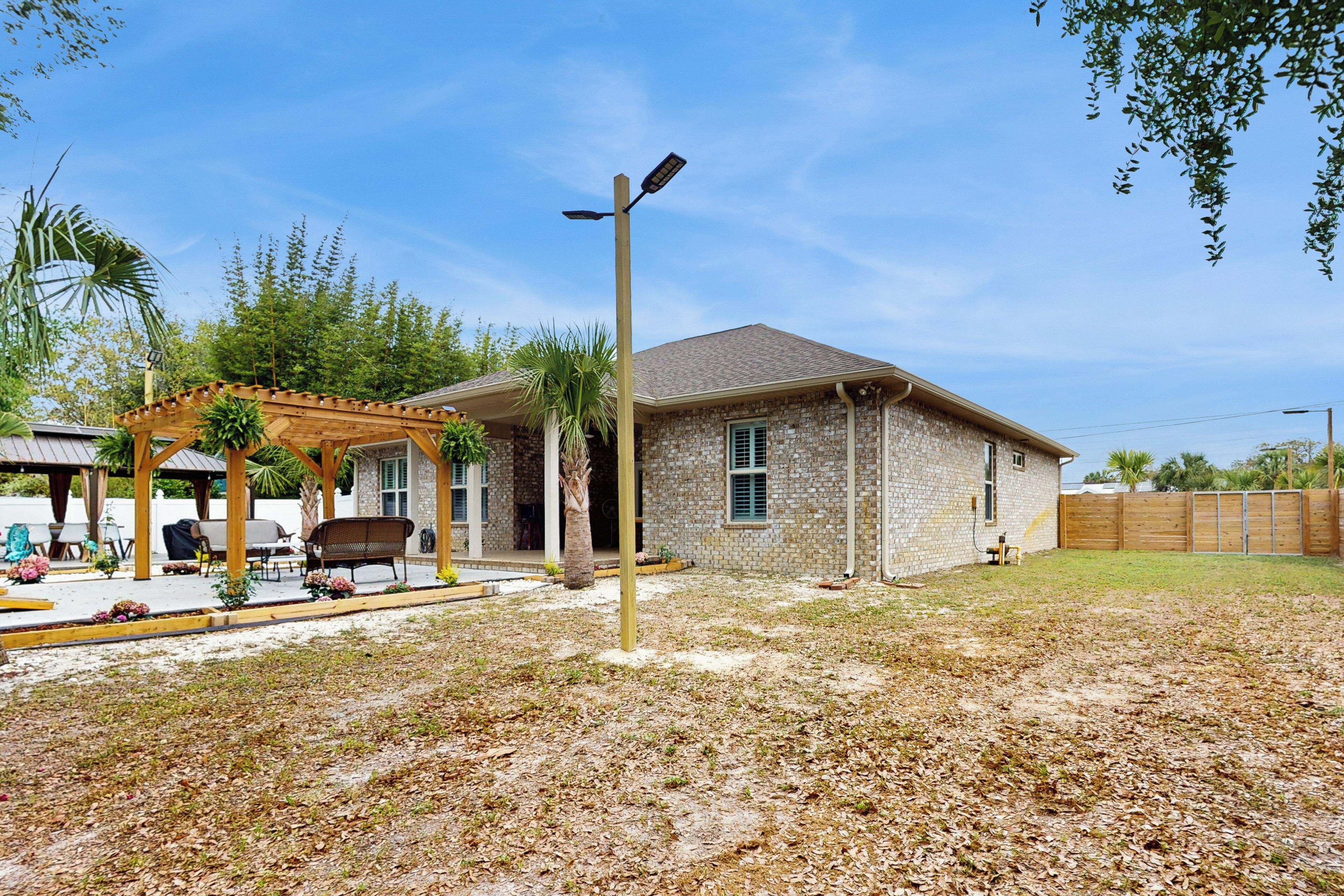 A house with a stone exterior, a wooden pergola, and a clear blue sky.
