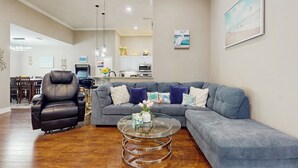 A living room with a grey sectional sofa, a glass coffee table, and a leather recliner. - 2 Mi to Beach! Group-friendly Navarre Getaway (Navarre)