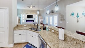 A modern kitchen with granite countertops, white cabinets, a built-in oven, and a ceiling fan. - 2 Mi to Beach! Group-friendly Navarre Getaway (Navarre)