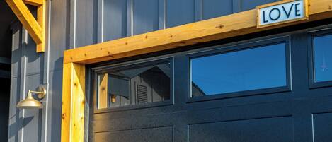 A garage door with a "LOVE" sign above it, a wooden beam, and a light fixture on the wall.