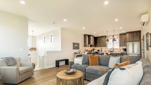 Ein großzügiges Wohnzimmer mit grauem Sofa, einem Holztisch und einer Treppe zu einer oberen Ebene.