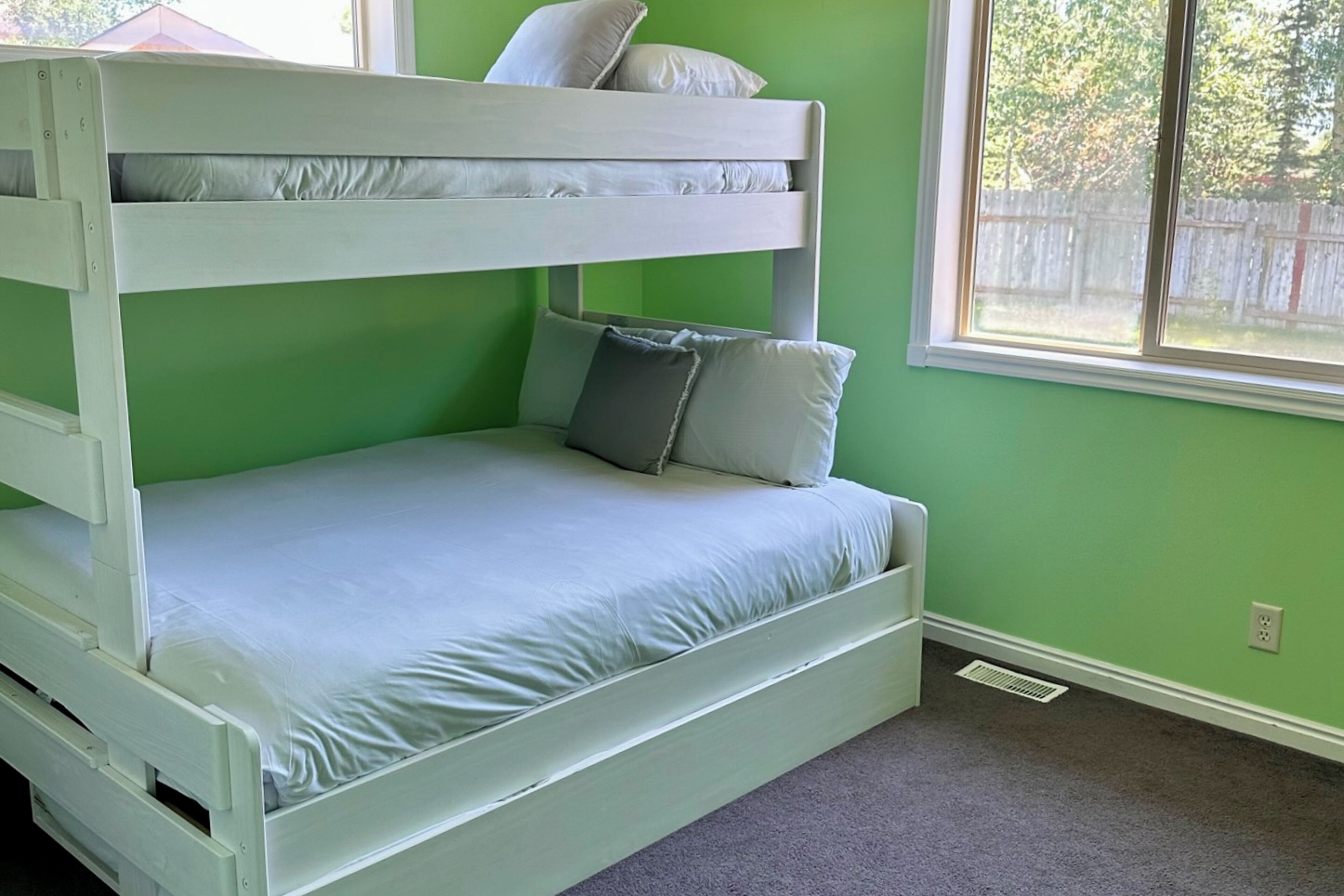 A bunk bed with a lower bunk and a single bed, both with white bedding.