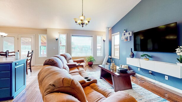 A modern living room with a sectional sofa, a flat-screen TV, and a dining area with a kitchen island.
