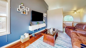 A living room with a flat-screen TV, wooden coffee table, and a brown leather sofa.