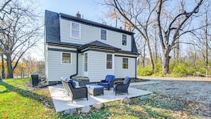 A two-story house with a patio area featuring wicker furniture and a stone fireplace. - Home w/ Spacious Yard, 3 Mi to Dtwn Des Moines! (Des Moines)