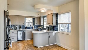 A modern kitchen with a central island, stainless steel appliances, and a view of the outside. - Home w/ Spacious Yard, 3 Mi to Dtwn Des Moines! (Des Moines)